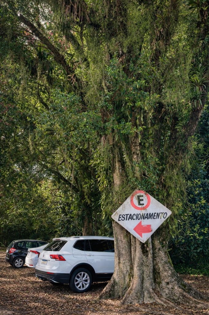 Estacionamento arborizado com placa indicando vagas na Churrascaria Beber